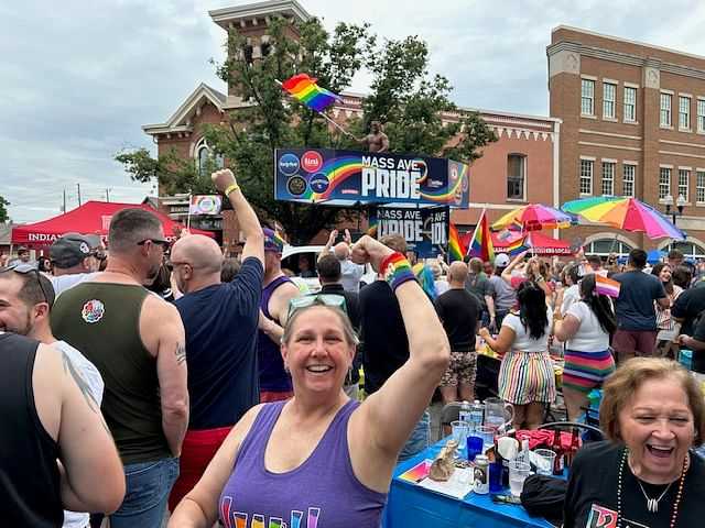 Crowd celebrating at Mass Ave Pride event with colorful flags and banners in a festive atmosphere.